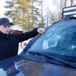 Mattias Heed med sin bil som någon eller några slagit sönder efter att han avlivat en trafikskadad varg. Foto: Boo Westlund