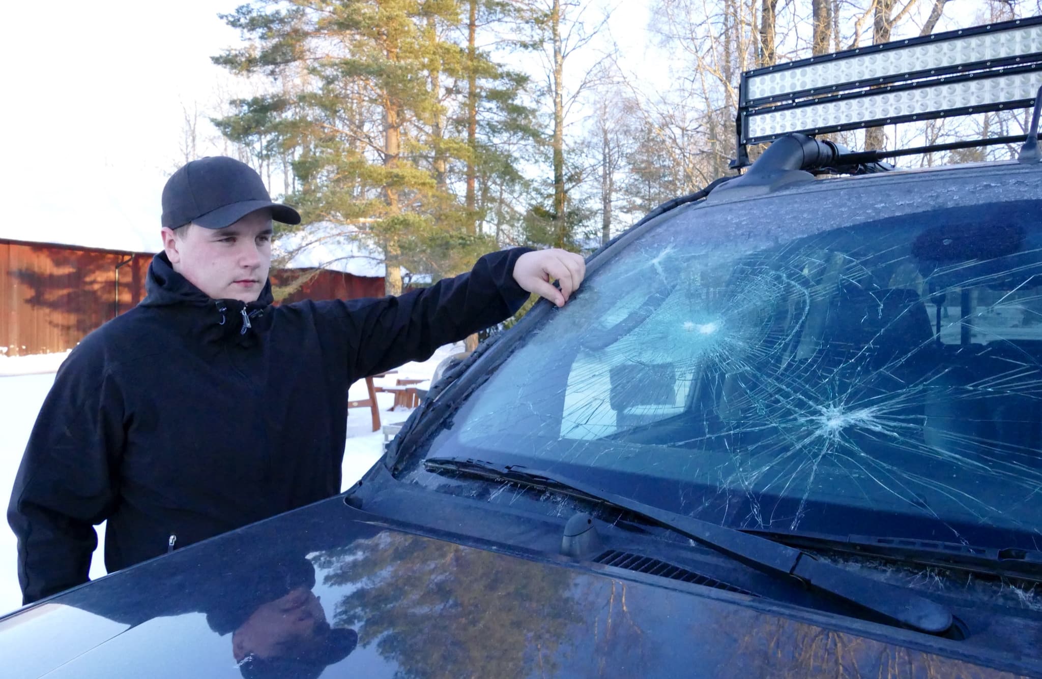 Mattias Heed med sin bil som någon eller några slagit sönder efter att han avlivat en trafikskadad varg. Foto: Boo Westlund